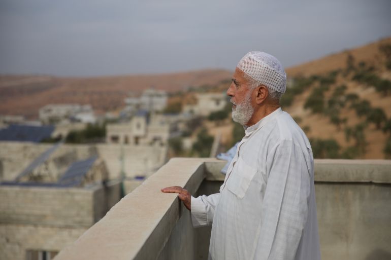 An elderly man stares across a rooftop in Idlib, Syria