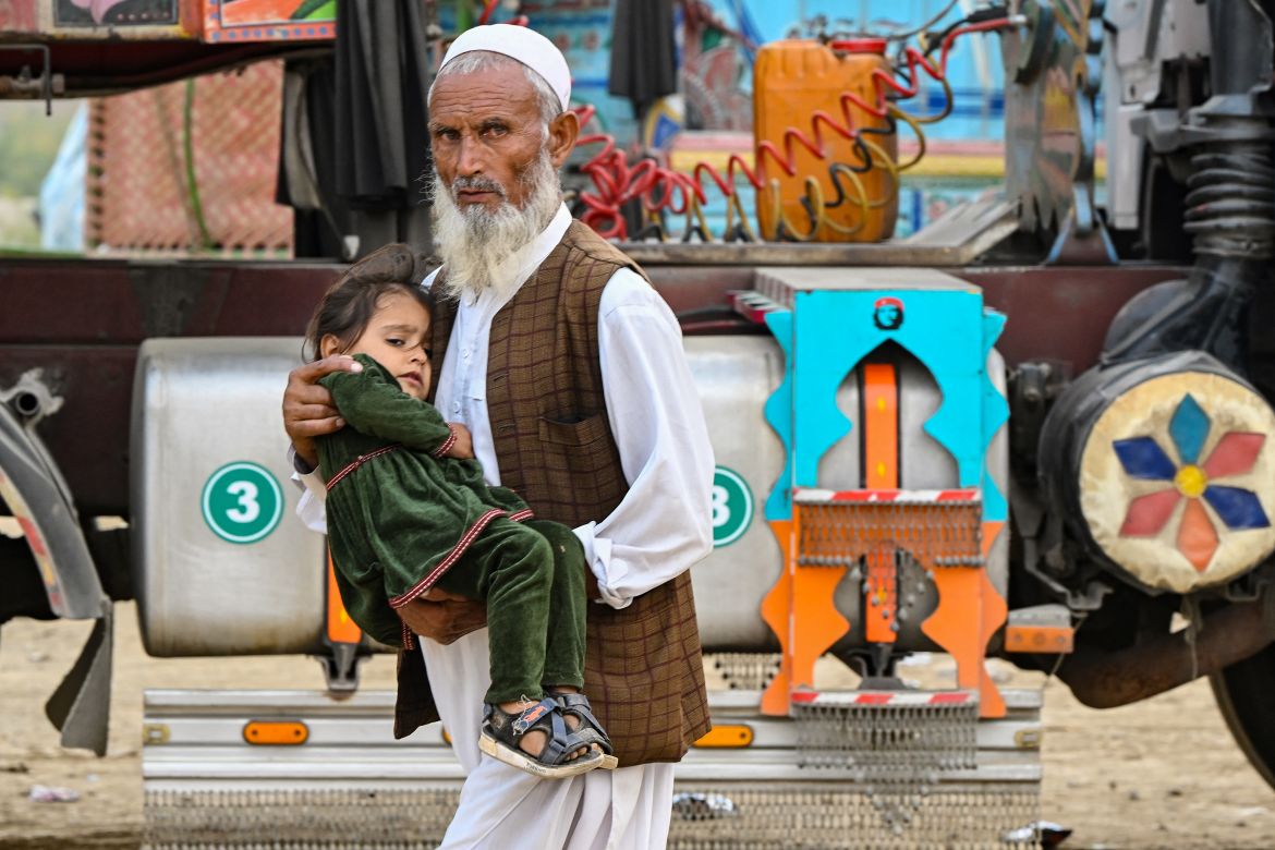 An Afghan refugee man carries a child as he prepares to depart for Afghanistan, at a holding centre in Landi Kotal.