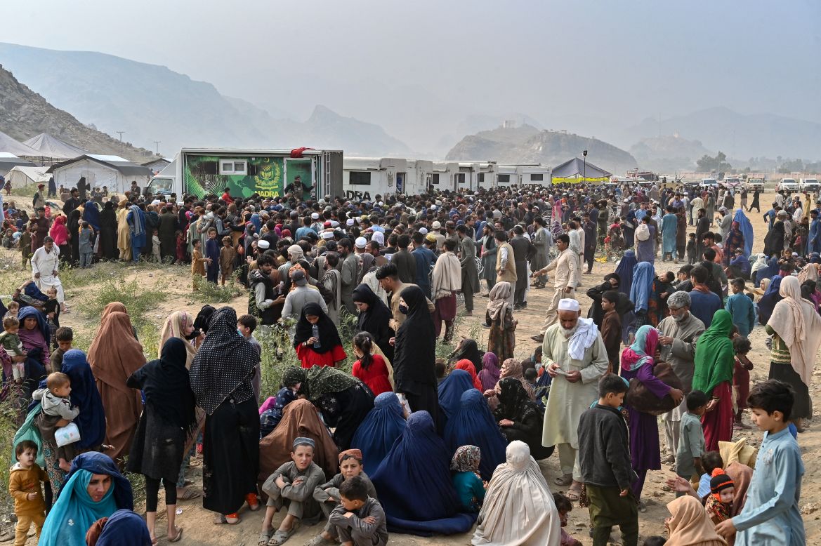 Afghan refugees gather around National Database and Registration Authority (NADRA) vans for biometric verifications as they prepare to depart for Afghanistan, at a holding centre in Landi Kotal.