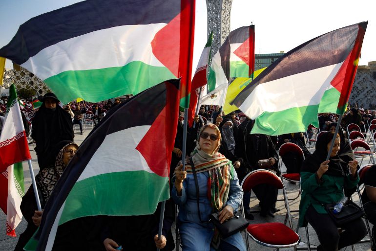 People wave Palestinian flags as they gather in the Imam Hussein square in Tehran