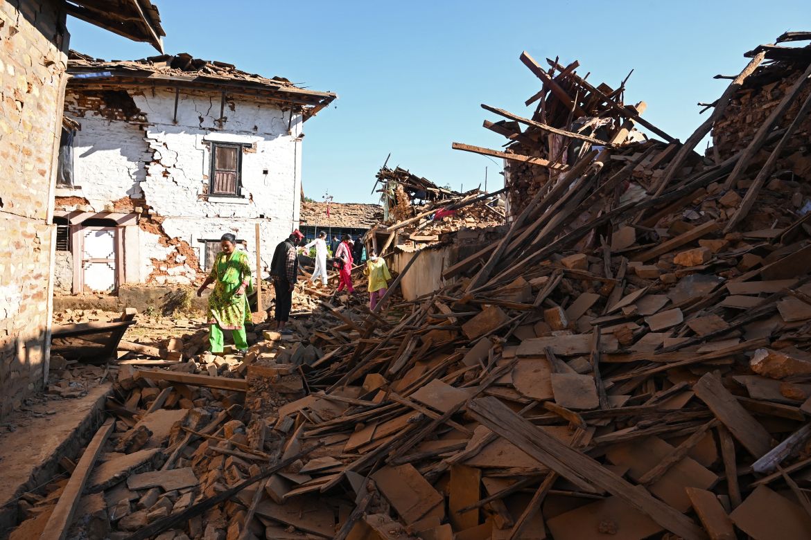 People walk through ruins of houses in the aftermath of an earthquake