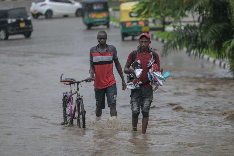 Pedestrians walk in a flooded street in the town of Nyali, after nightlong heavy rainfall in Mombasa on November 3, 2023. (Photo by SIMON MAINA / AFP)