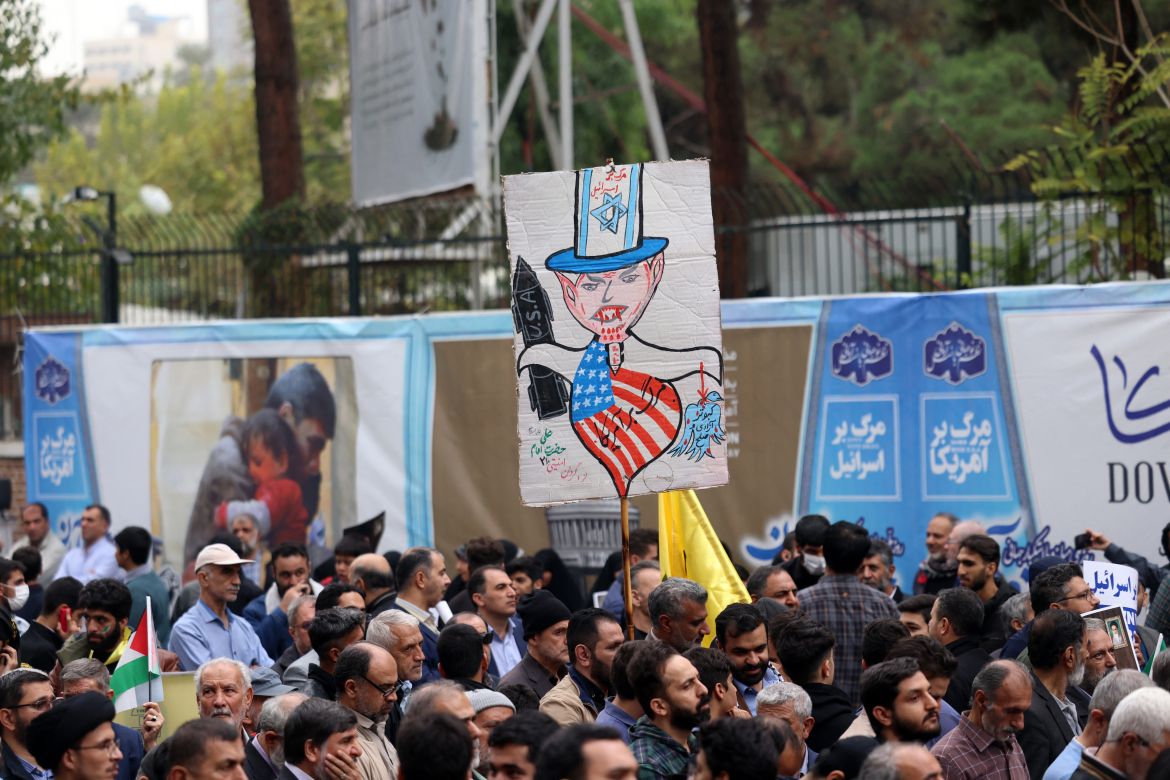 Iranians lift placards during a rally outside the former US embassy in Tehran, to support the Palestinians of the Gaza Strip and to mark the 44th anniversary of the start of the Iran hostage crisis.