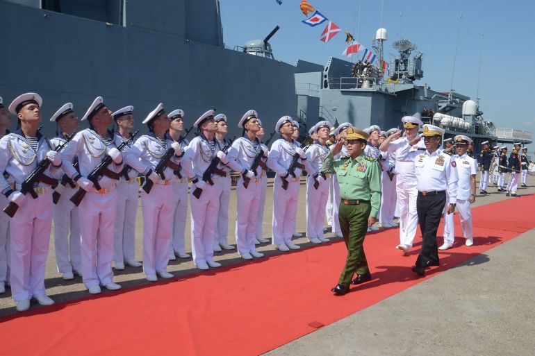 Myanmar's Senior General Min Aung Hlaing reviewing Russian sailors standing to attention with their rifles. Min Aung Hlaing is saluting.