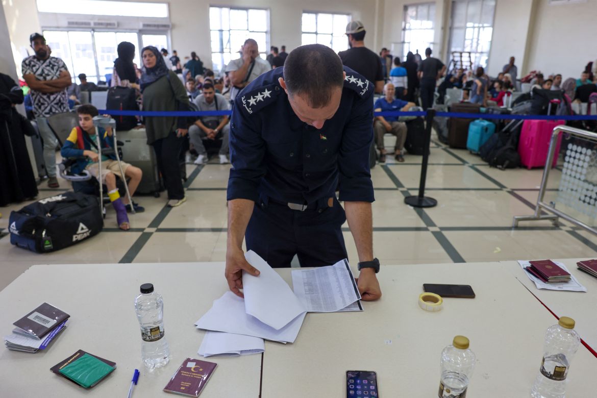 A Palestinian border guard checks the documents of dual nationals and foreigners as they wait to cross the Rafah border crossing with Egypt, in the southern Gaza Strip