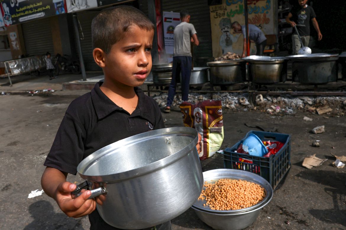 A child carries a pot as Palestinians cook in a street in Rafah in the southern Gaza Strip.
