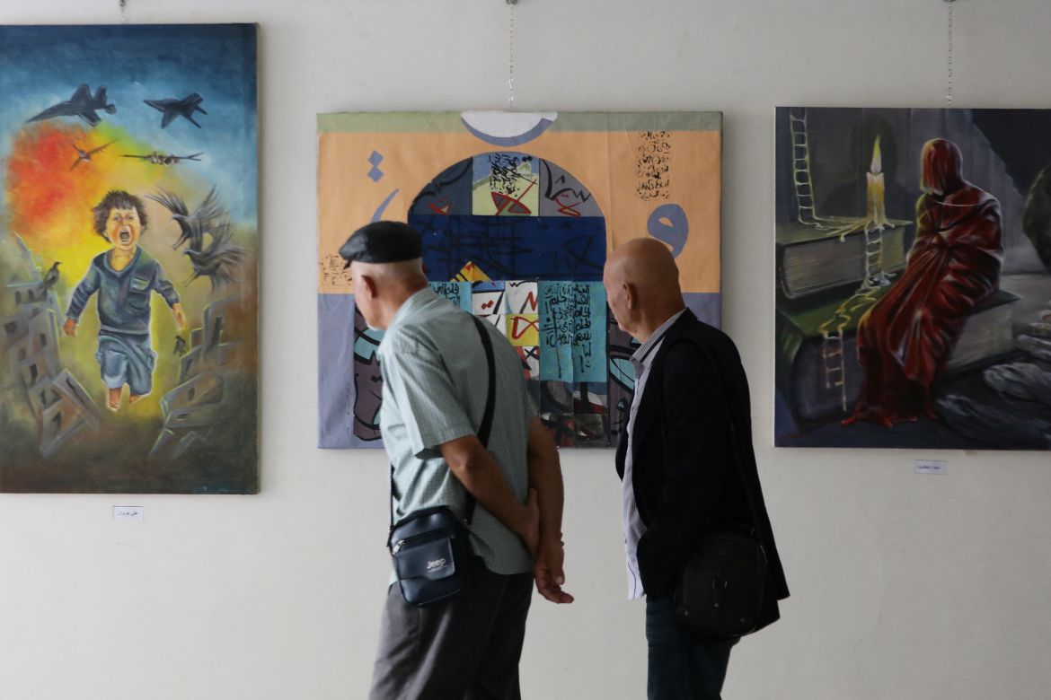 Visitors look at art works depicting the war in Gaza during an exhibition by Syrian and Palestinian visual artists in solidarity with the Palestinians in Damascus.