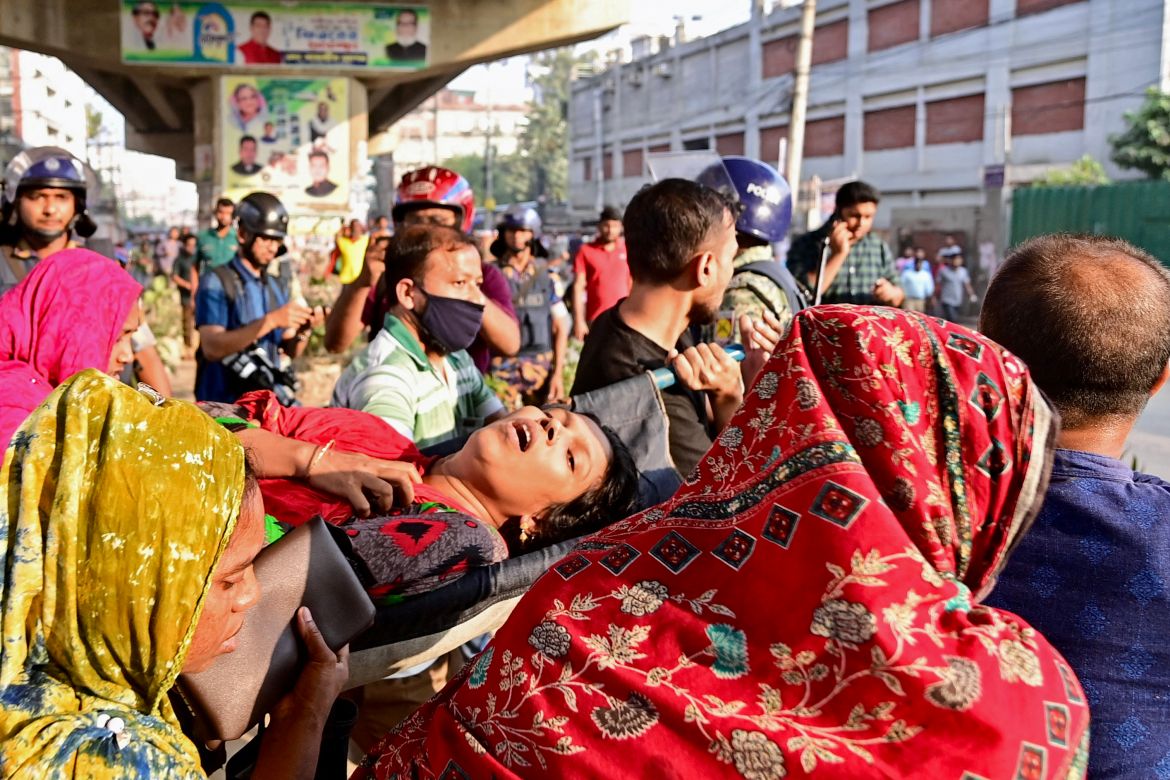 Garment workers carry a fellow worker (C) injured during a clash with police personnel in Gazipur.