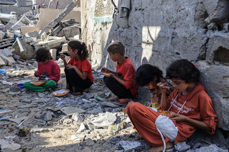 Amal al-Robayaa's children eat their meal amid the ruins of the family home destroyed in an Israeli strike in Rafah