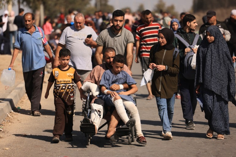 Palestinian families fleeing Gaza City and other parts of northern Gaza for the southern areas walk along a road on November 10, 2023 [MAHMUD HAMS / AFP]