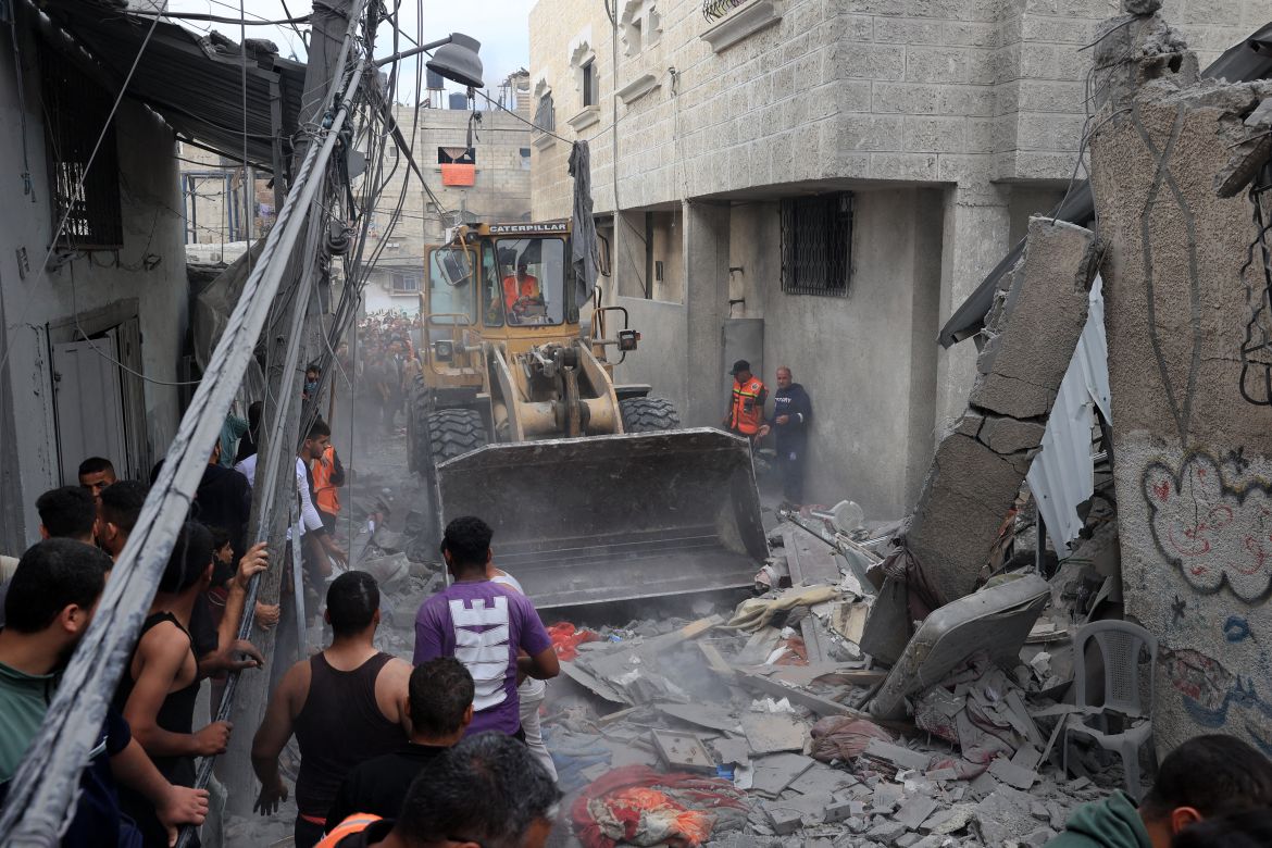 An excavator clears away debris to allow rescuers to reach victims following Israeli bombing on Rafah