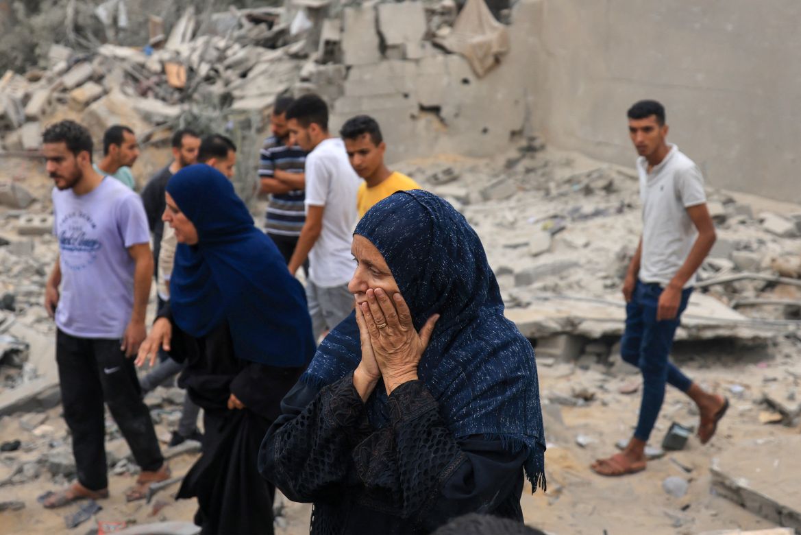 A woman reacts as people stand amid the rubble of a destroyed building following an Israeli bombardment in Khan Yunis in the southern Gaza Strip.