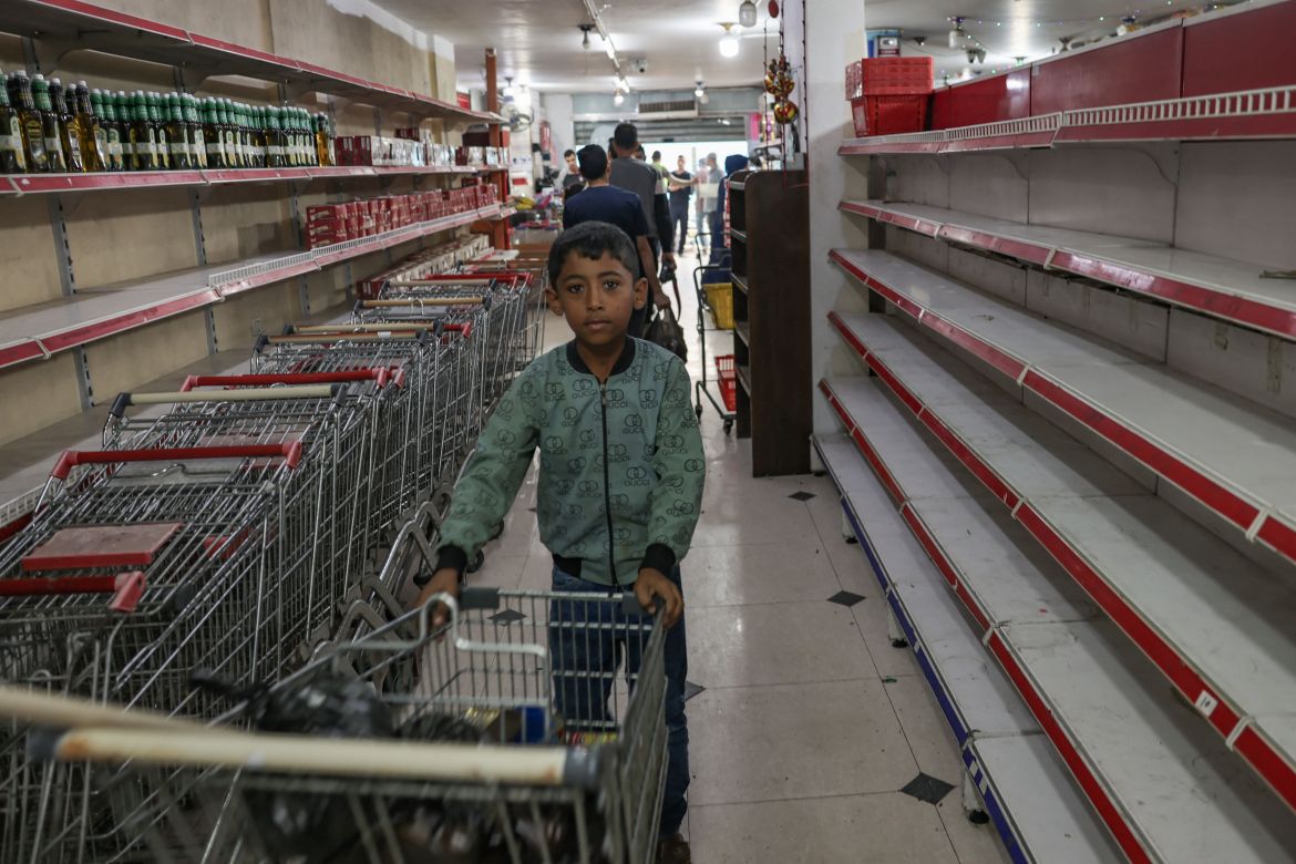 A Palestinian boy stands near empty shells at a supermarket in Rafah, in the southern Gaza Strip