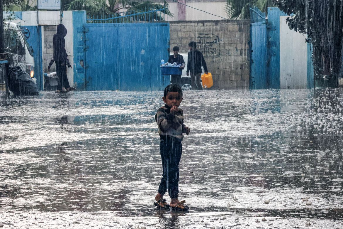 A boy stands in the rain at a school run by the United Nations Relief and Works Agency for Palestine Refugees in the Near East (UNRWA) in Rafah in the southern Gaza Strip on November 14