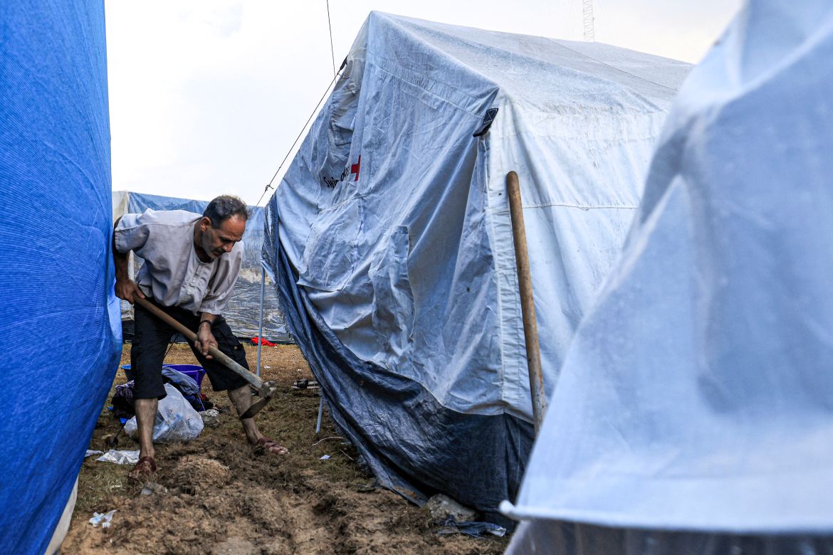 A man digs with a shovel outside a tent among others pitched by Palestinians taking shelter from Israeli bombardment around Nasser Hospital, in Khan Yunis in the southern Gaza Strip on November 14