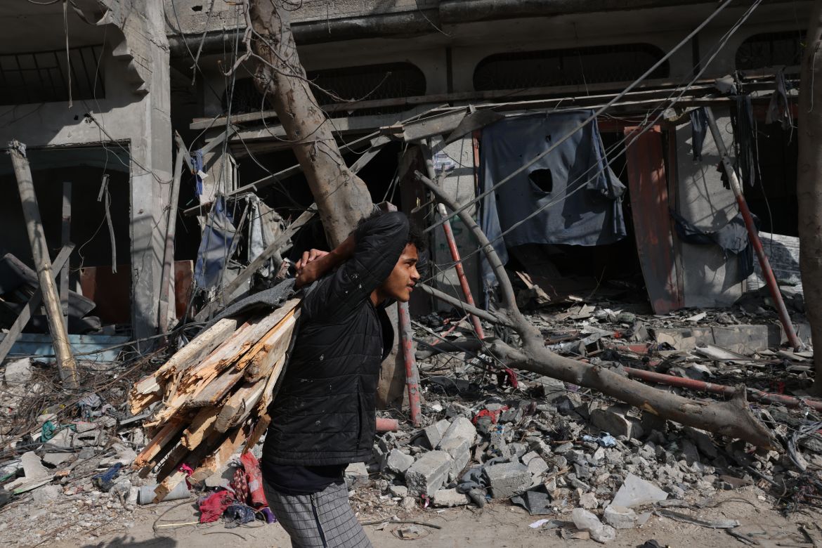A Palestinian man collects firewood from fallen trees outside buildings destroyed during the Israeli bombardment of Gaza in Bureij, in the central of Gaza Strip.