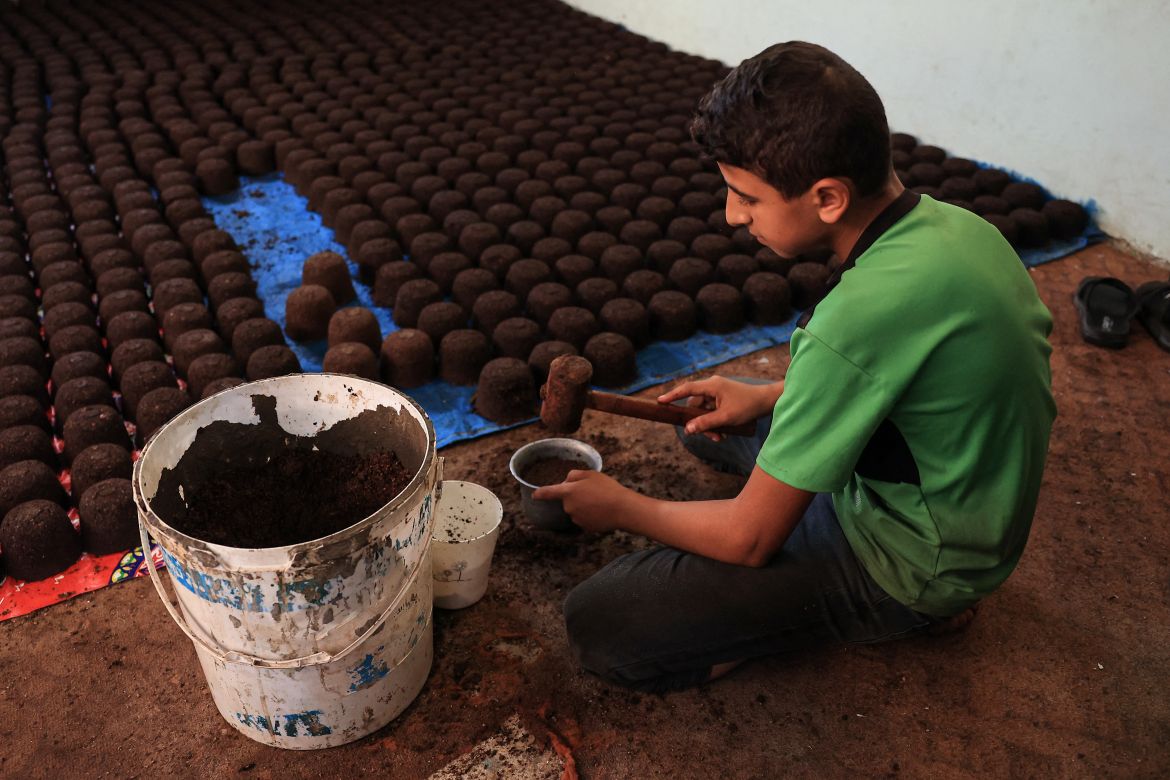 A Palestinian youth manufactures a mixture of crushed olive pits to be used as fire starter amid fuel shortages in Rafah, in the southern Gaza Strip.