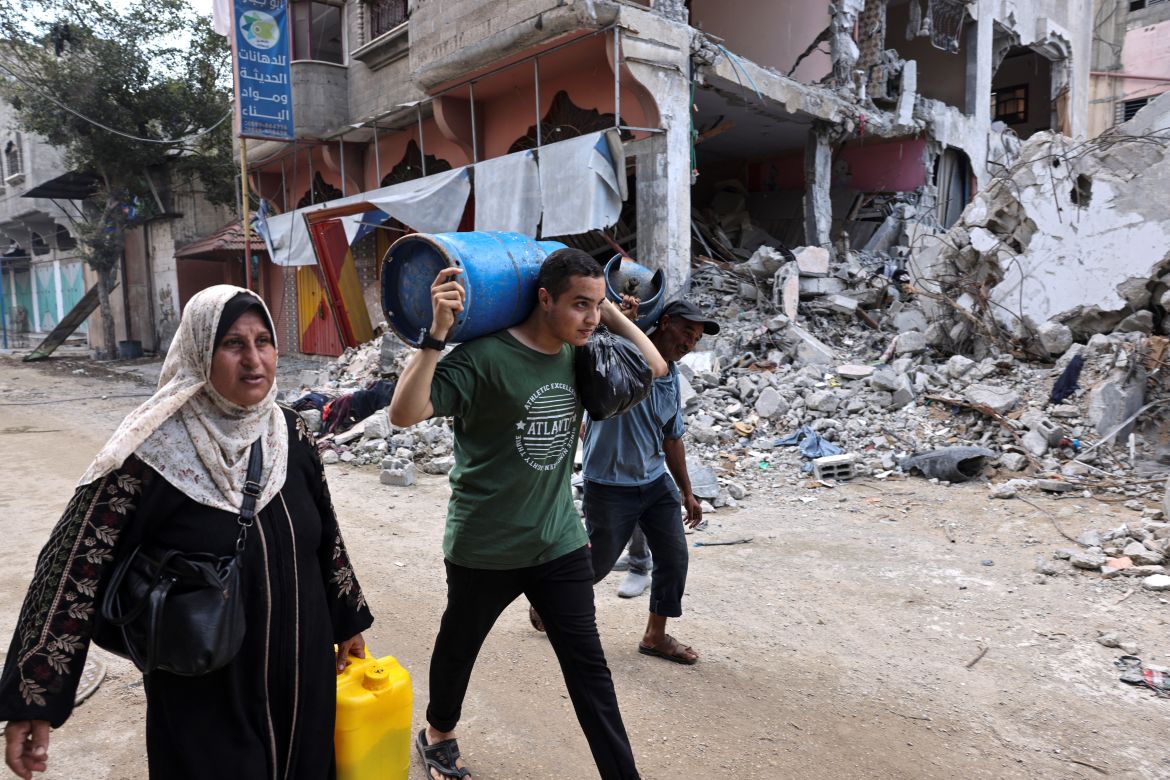 A Palestinian youth carries a gas cylinder past buildings destroyed during the Israeli bombardment of Gaza in Bureij, in the central of Gaza Strip.