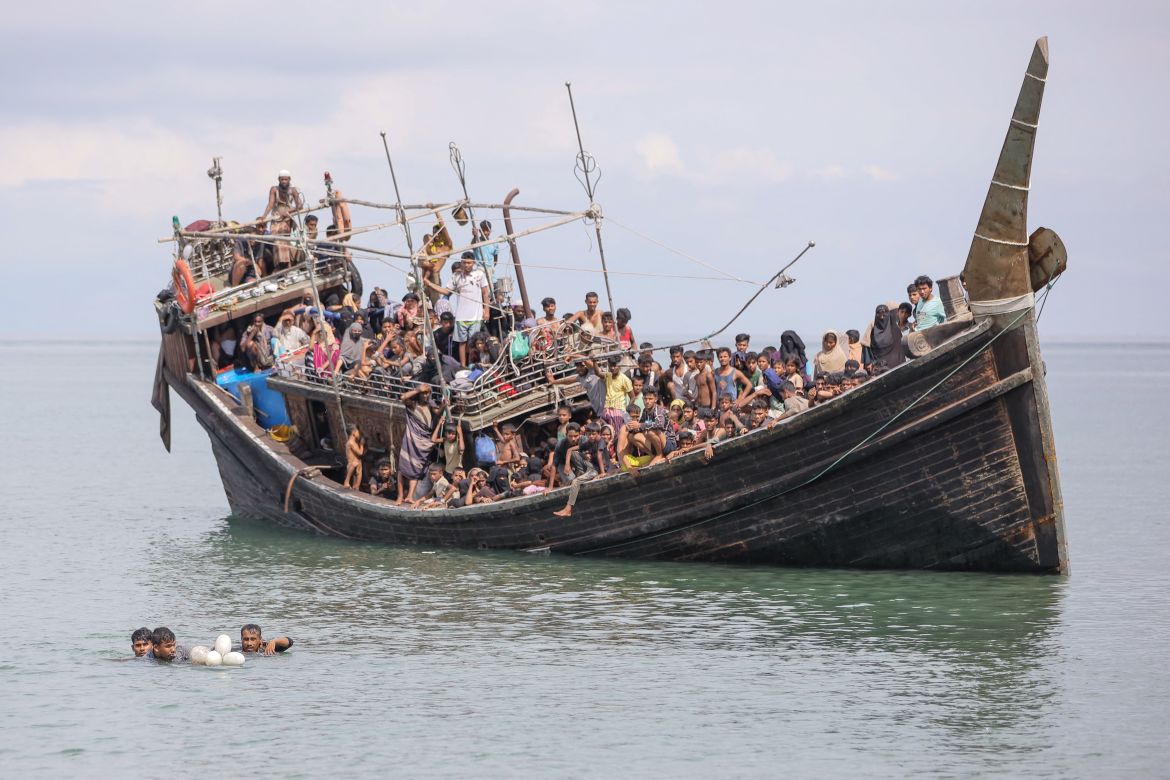Three newly arrived Rohingya refugees try to swim to the beach as they are stranded on a boat after the nearby community gave them water and food but did not allow them to land in Pineung, Aceh province