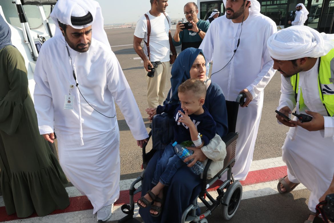 Emiratis speak with a Palestinian mother carrying her child their arrival in Abu Dhabi on November 18, 2023, after being evacuated from Gaza as part of a humanitarian mission organised by the United Arab Emirates