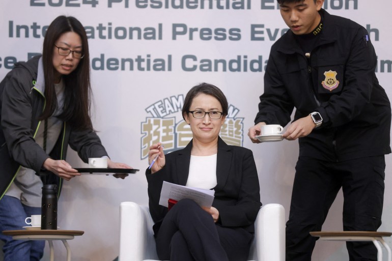 Democratic Progressive Party (DPP) vice presidential candidate Hsiao Bi-khim. She is sitting on a chair on stage. Two people on either side are bringing cups of tea.