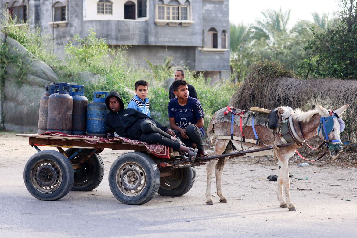 Children use a donkey-pulled cart to transport empty gas canisters to be filled with cooking gas from a tank that entered the Palestinian enclave via the Rafah crossing with Egypt, in Rafah in the southern Gaza Strip on November 25