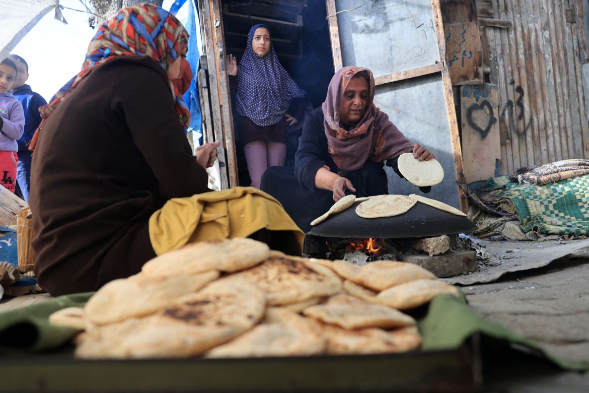 Women bake bread using a makeshift wood stove in Rafah in the southern Gaza Strip on November 25