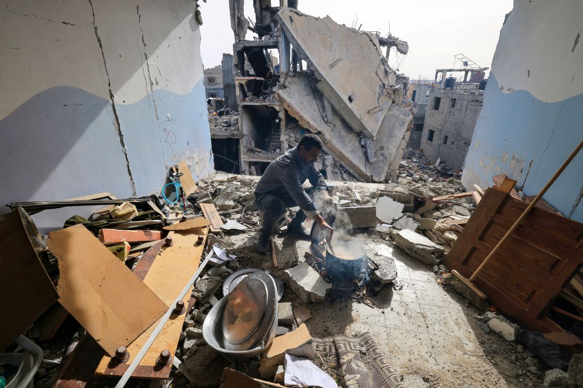 A Palestinian man cooks inside his damaged apartment in the Khezaa district on the outskirts of the southern Gaza Strip city of Khan Yunis, following weeks of Israeli bombardment.