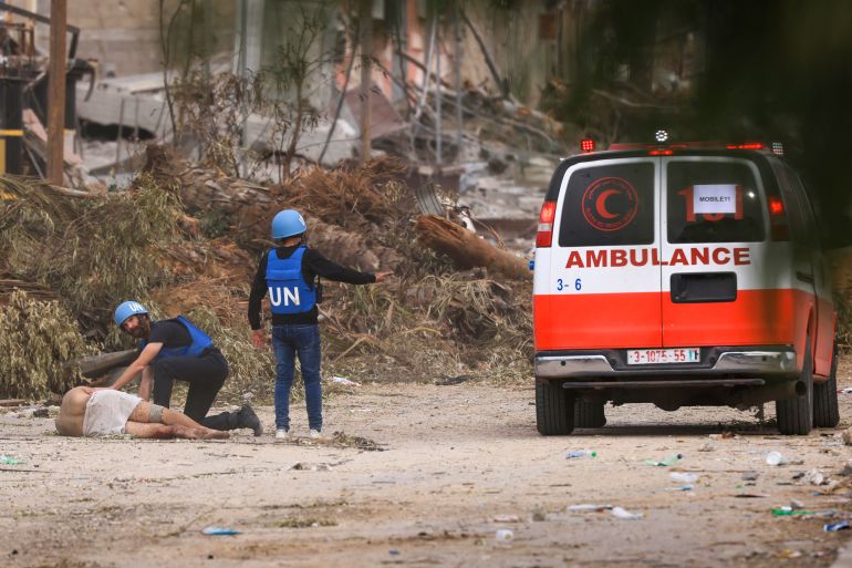 UN staff approach a wounded Palesinian reportedly shot by Israeli forces while leaving Gaza City through the Zeitoun district on its southern entrance to carry him into an ambulance on November 25