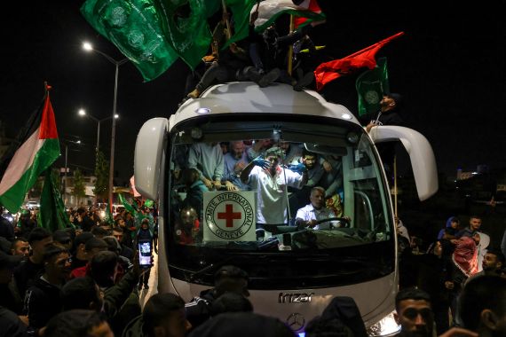 Geceleri bir kalabalık, üzerinde Filistin bayrakları bulunan bir otobüsün etrafını sarıyor