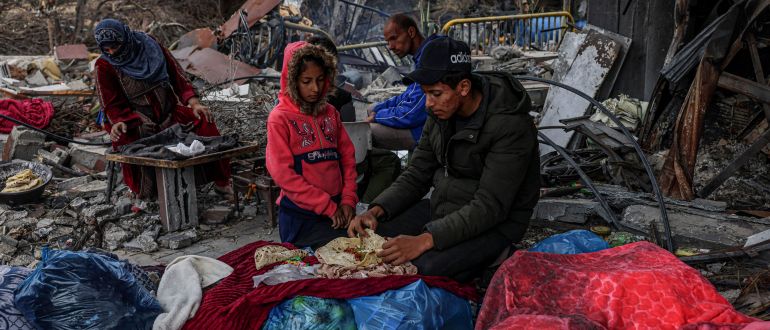 Palestinians eat outside amid the destruction caused by Israeli strikes in the village of Khuzaa, east of Khan Yunis near the border fence between Israel and the southern Gaza Strip on November 27, 2023, amid a truce in battles between Israel and the Palestinian militant group Hamas. – The Israeli government said today it had put Hamas “on notice” that an “option for an extension” of the truce in the Gaza Strip was open. (Photo by SAID KHATIB / AFP)