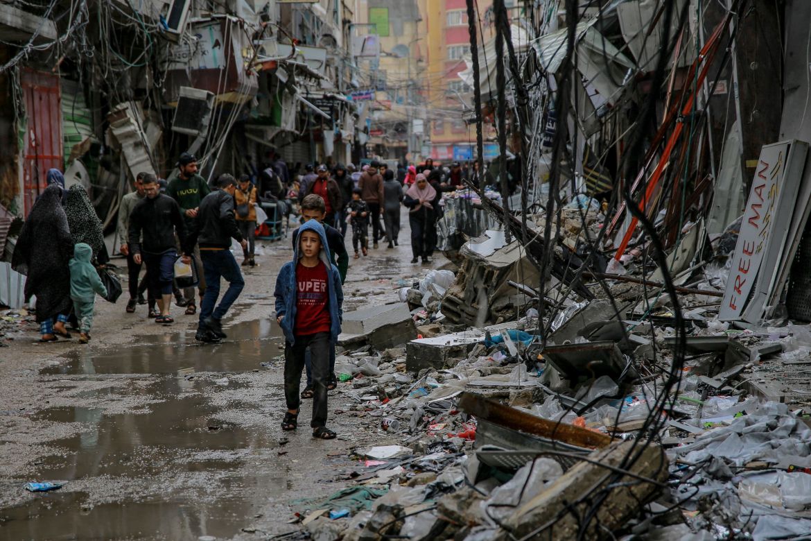 Palestinians walk amid debris of buildings hit in Israeli strikes, near Al-Zawiya market in Gaza City.