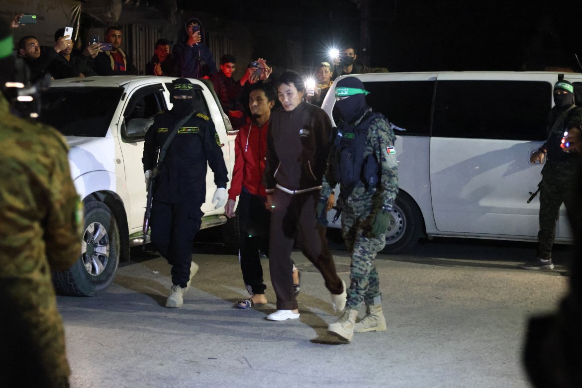 Hamas and Islamic Jihad fighters accompany newly released hostages before handing them over to the Red Cross in Rafah, in the southern Gaza Strip on November 28