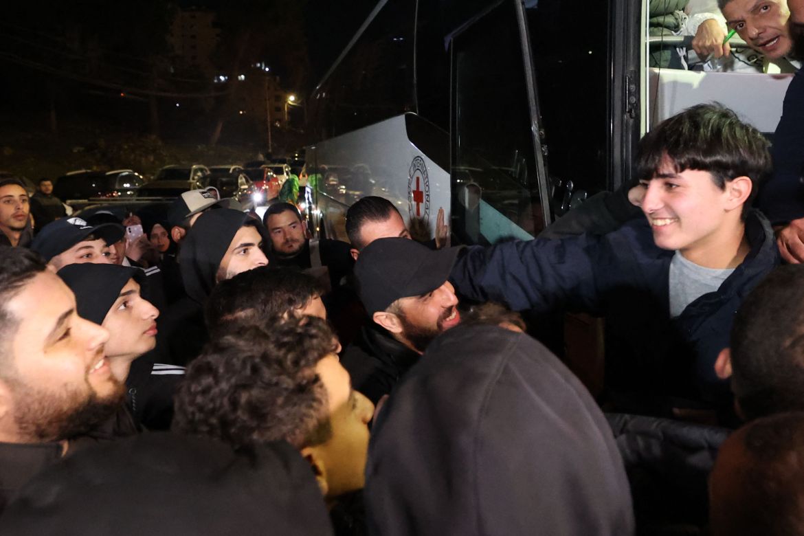 A newly released Palestinian prisoner (R) greets friends and relatives while disembarking a Red Cross bus transporting prisoners freed from Israeli jails.