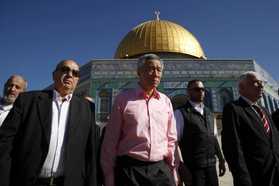 Lee Hsien Loong visiting the Al Aqsa Moswue. He is wearing a pink shirt. The golden dome is behind him.