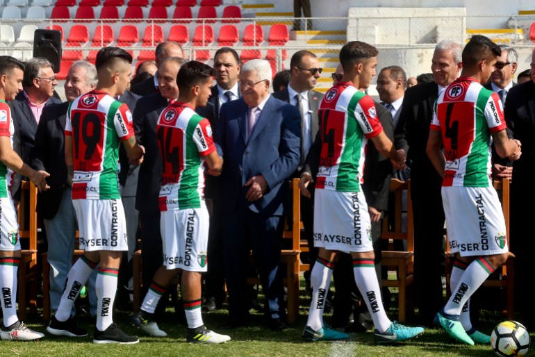 A row of footballers walks alongside a line of politicians, shaking hands