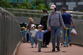 Woman and child in protective masks walk across a bridge.