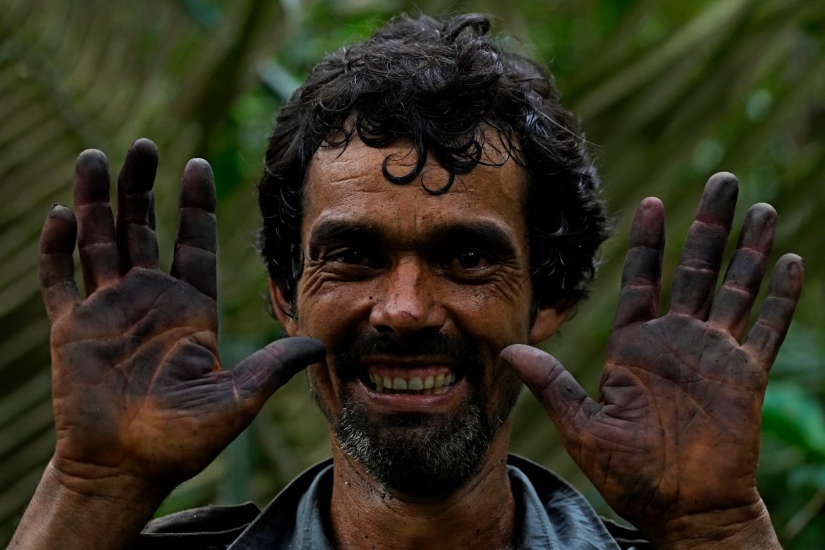Edson Polinario holds up his hands dyed blue after handling Acai fruit berries in the forest of a rural area of his property in the municipality of Nova California, state of Rondonia, Brazil.