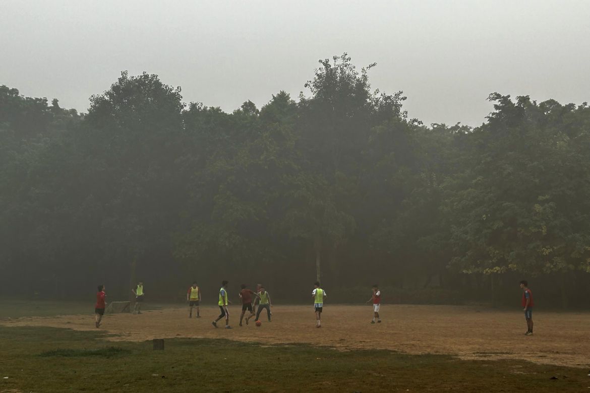 Children play soccer early morning in a park enveloped by smog and fog in New Delhi