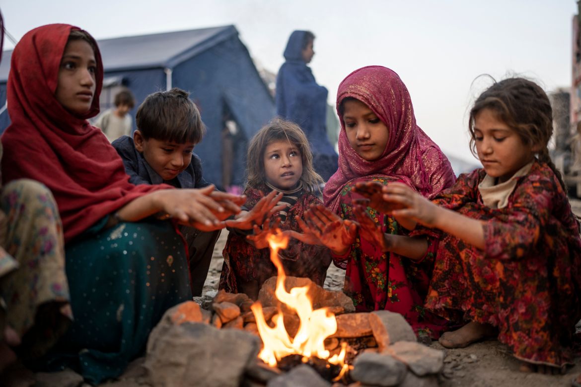 Afghan refugee children warm themselves with fire in a camp near the Torkham Pakistan-Afghanistan border in Torkham, Afghanistan.