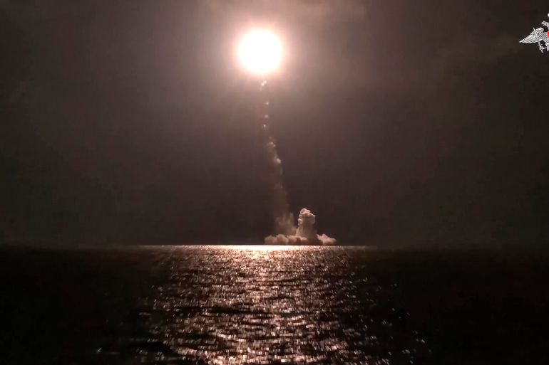 A photo released by Russian Defense Ministry Press Service shows a Bulava intercontinental ballistic missile being fired from a submarine. It is dark, The streak of the missile and a white/orange explosion can be seen.