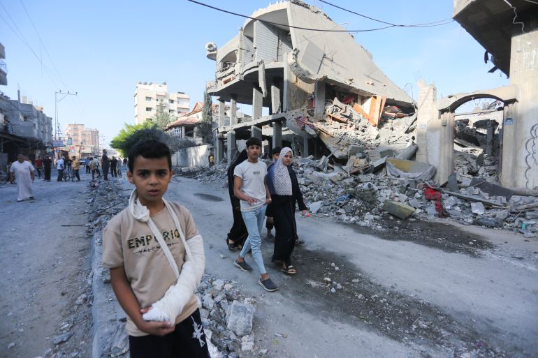 Palestinians walk by buildings destroyed in the Israeli bombardment of the Gaza Strip in Rafah, Tuesday,
