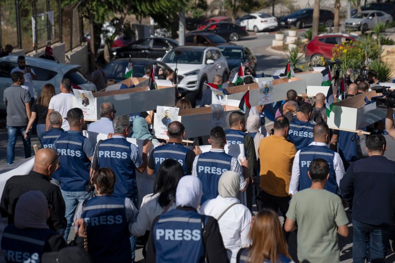Palestinian journalists carry mock coffins of Palestinian journalists who were killed during the current war in Gaza during a symbolic funeral toward a United Nations office, in the West Bank city of Ramallah