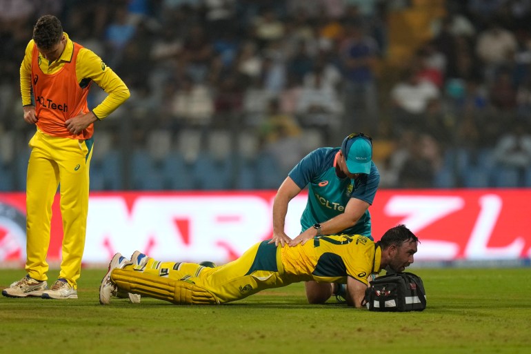 Australia's Glenn Maxwell, on ground, is attended by a member of team support staff during the ICC Men's Cricket World Cup match between Australia and Afghanistan in Mumbai, India, Tuesday, Nov. 7, 2023. (AP Photo/Rajanish Kakade)