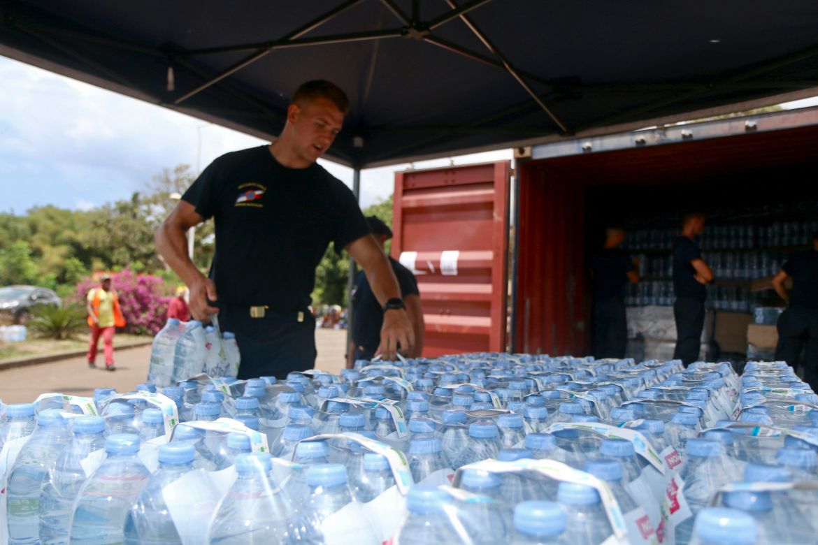 A security officer picks up water bottles for residents in Tsoundzou, on the French Indian Ocean territory of Mayotte.
