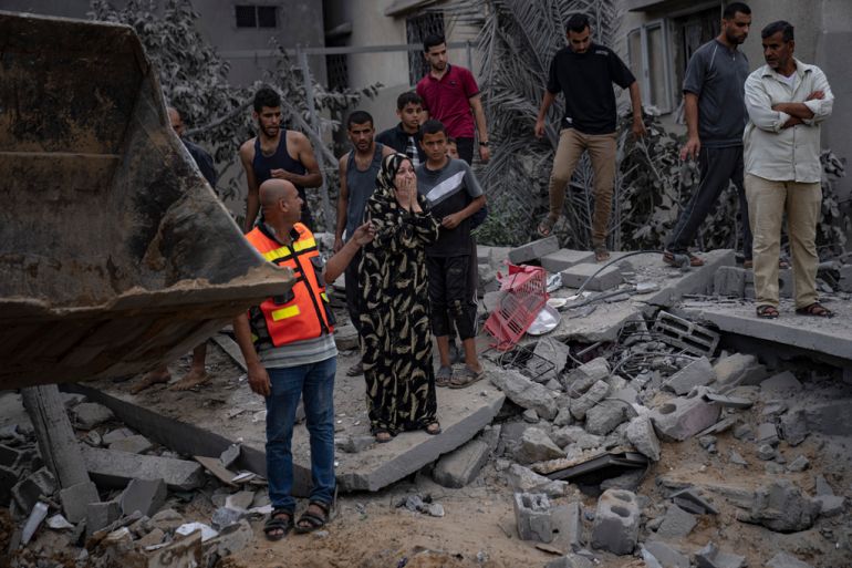 Palestinians stand on rubble in the aftermath of an Israeli airstrike