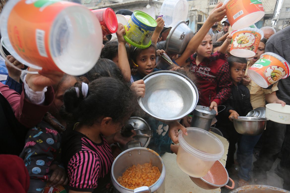 Palestinians line up for food during the ongoing Israeli bombardment of the Gaza Strip in Rafah on Monday