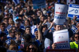 Participants hold signs reading "America Stands with Israel" as they stand on the National Mall at the March for Israel.