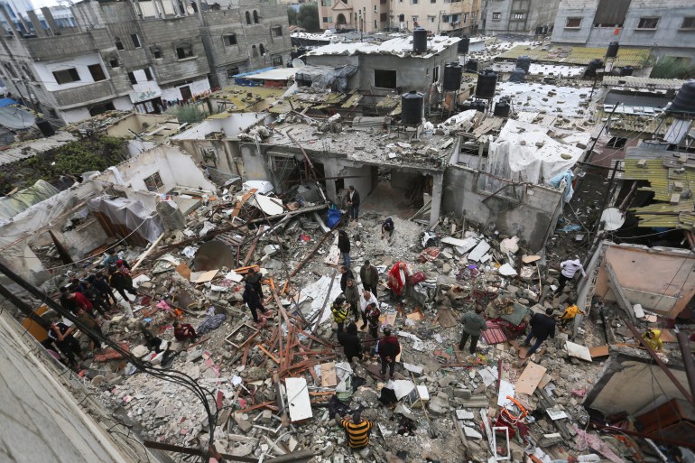 Os palestinos olham para a destruição após os ataques israelenses em Rafah, na Faixa de Gaza.
