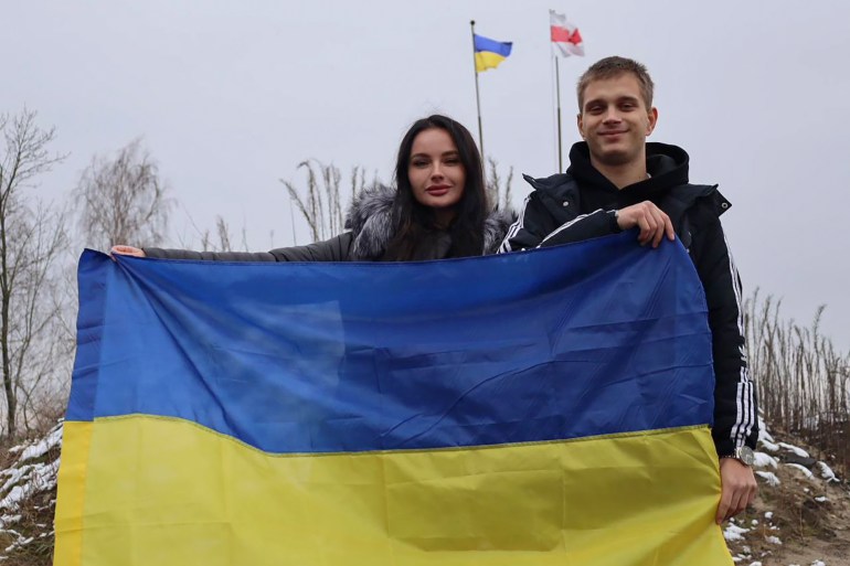 Ukrainian teenager Bohdan Yermokhin, right, holds the Ukraine flag on the Ukraine-Belarus border 
